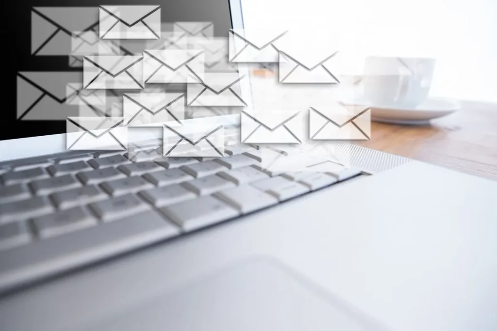 Tela de computador com ícones de envelopes representando e-mails sobre o teclado, simbolizando e-mail marketing e fluxo de mensagens eletrônicas